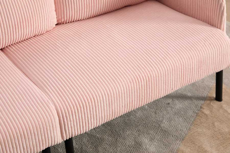 Close-up of a pink ribbed sofa with black legs on a carpeted floor.