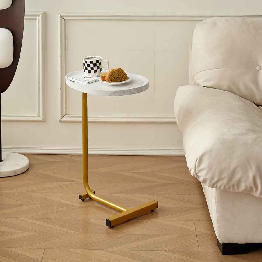 Small round white table with gold legs next to a beige sofa in a living room.