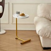 Small round white table with gold legs next to a beige sofa in a living room.