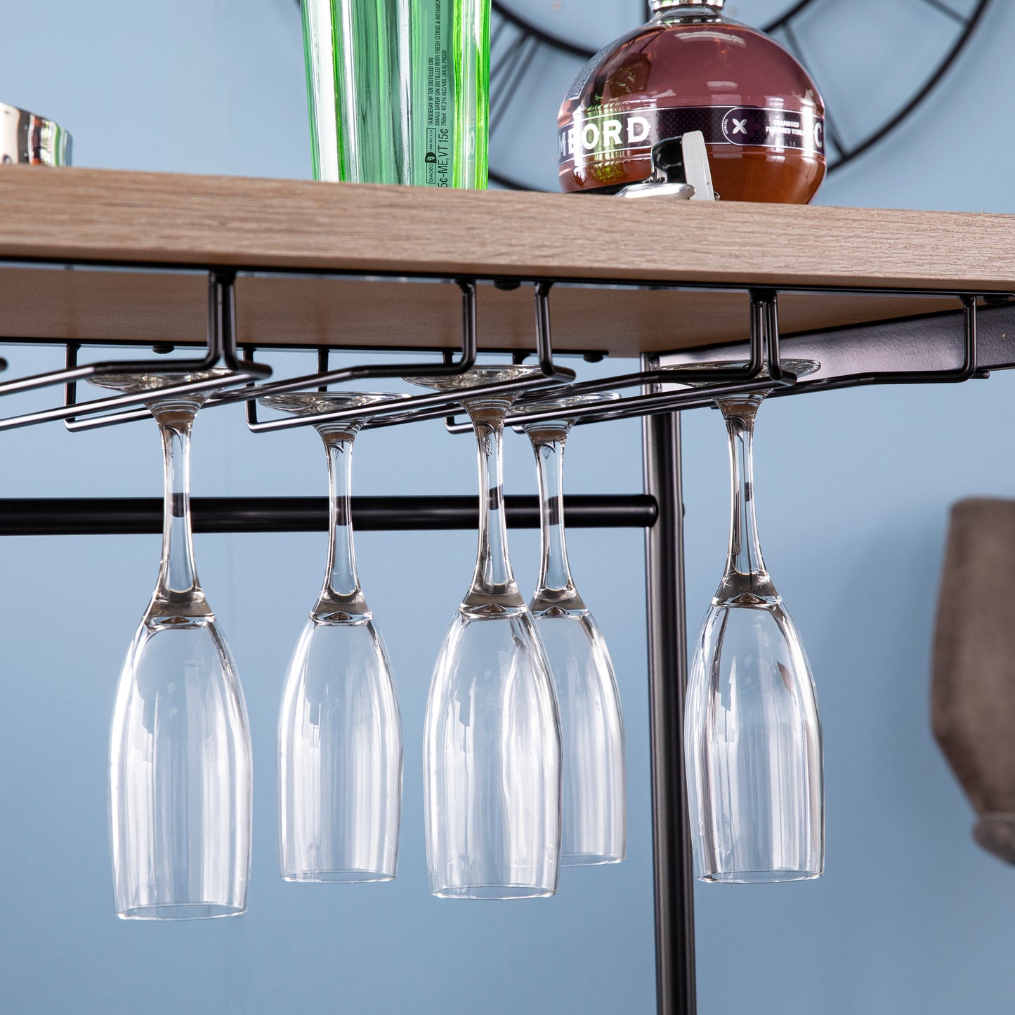 Under-table mounted glass rack on Dagney Wine Bar Table Storage holding hanging wine glasses, ideal for modern bar organization.