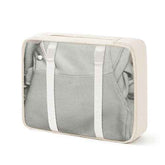 Cream-colored travel packing cube with mesh top and adjustable straps, designed for organizing clothes inside luggage