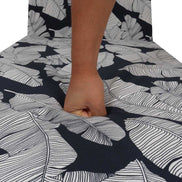 Person holding a piece of fruit under a black and white leaf-patterned tablecloth.