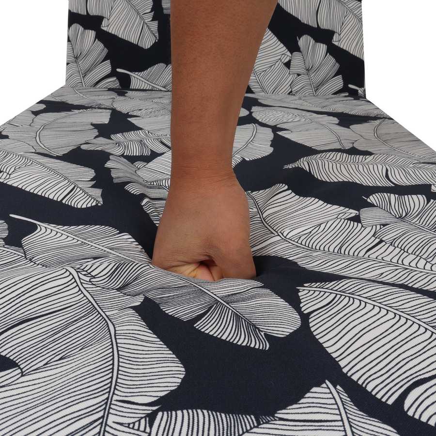 Person holding a piece of fruit under a black and white leaf-patterned tablecloth.