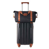 Black rolling travel duffel bag with brown accents and telescoping handle, suitable for business trips