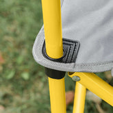 Close-up of a yellow metal frame with gray fabric and black fastener against a blurred natural background