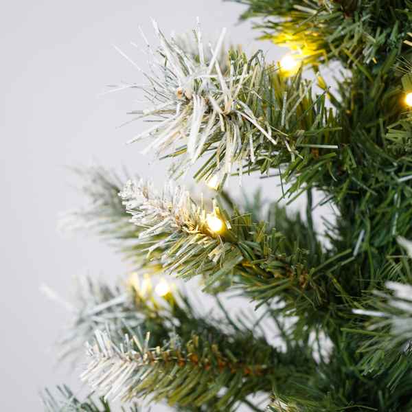 Close-up of a Christmas wreath with lights on a plain background