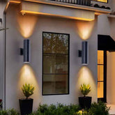 Modern outdoor wall lights on a building exterior with plants and a mirror.