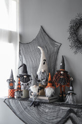 Halloween-themed gnomes with witch hats and costumes on a decorative tablecloth.