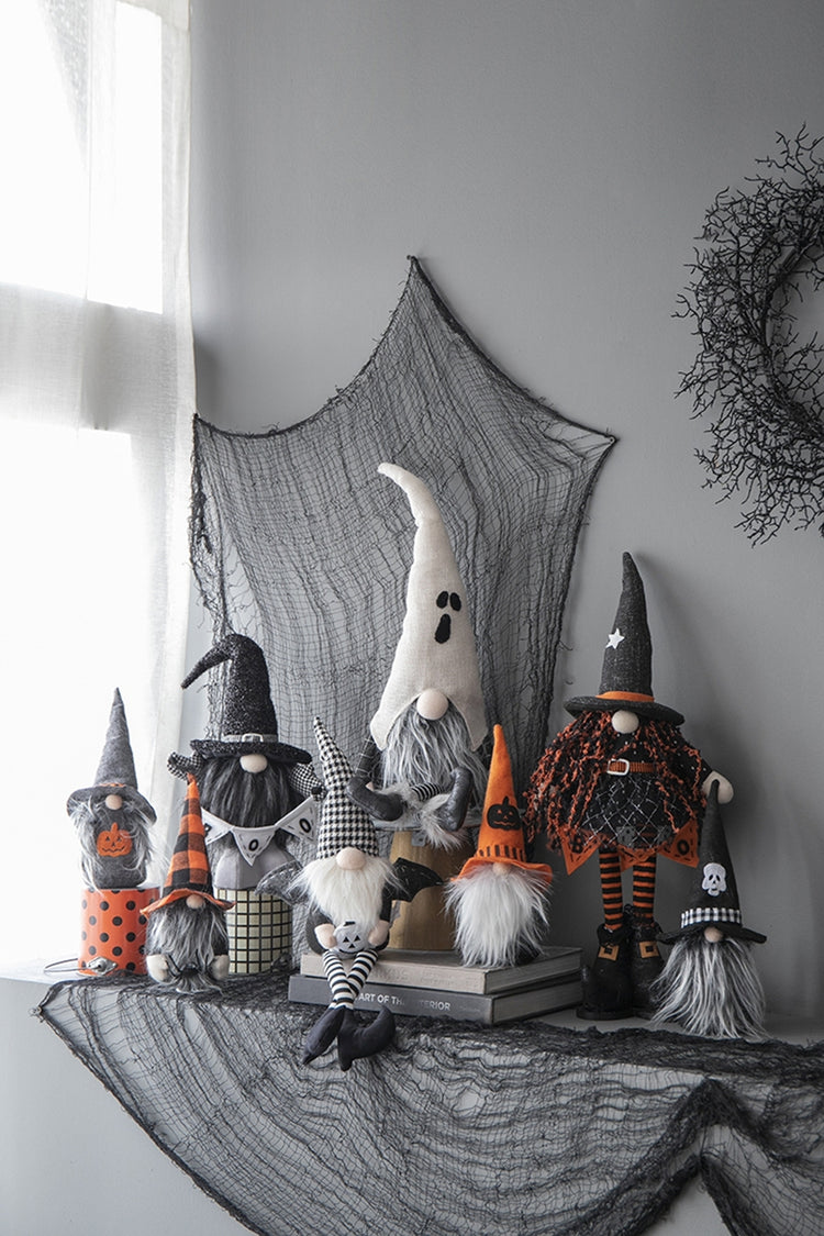 Halloween-themed gnomes with witch hats and costumes on a decorative tablecloth.