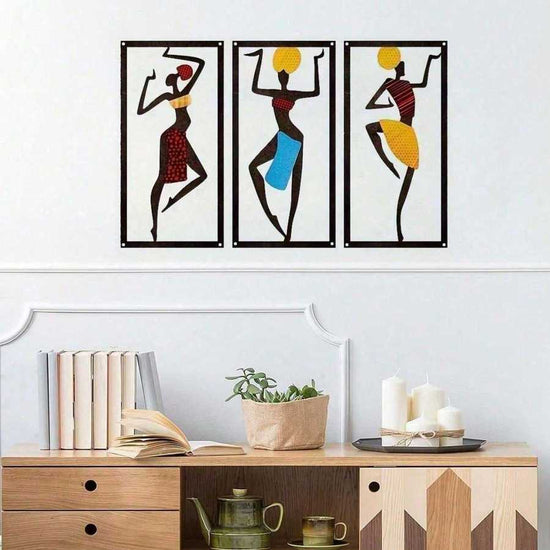 Bohemian Macrame Wall Hanging with African dancer design displayed above a wooden console with books, candles, and plants. Handmade decor in vibrant colors.