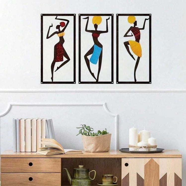 Bohemian Macrame Wall Hanging with African dancer design displayed above a wooden console with books, candles, and plants. Handmade decor in vibrant colors.