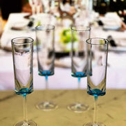 Set of 4 unbreakable blue acrylic champagne flutes arranged on a table, perfect for elegant gatherings and celebrations.