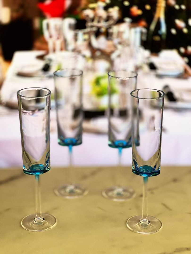 Set of 4 unbreakable blue acrylic champagne flutes arranged on a table, perfect for elegant gatherings and celebrations.