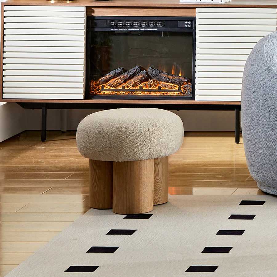 Modern living room with a fireplace, ottoman, and decorative rug.