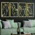 Four gold line art wall hangings on a black wall above a green sofa with decorative pillows.