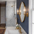 Bathroom with round gold mirror, sink, and wall lights.