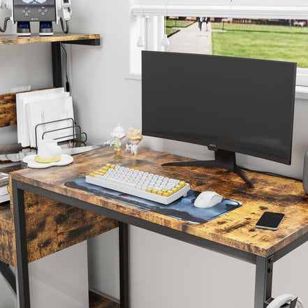 Desktop surface of computer desk with monitor, keyboard, and mouse, emphasizing spacious work area and rustic wood texture.