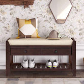 Wooden bench with cushion, shoes, and a hat on a floral wallpapered wall.