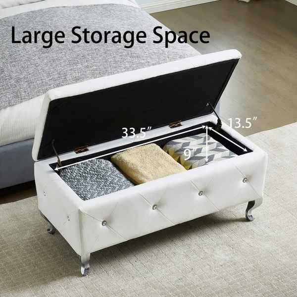 White storage ottoman with open lid showing interior dimensions and items, placed on a carpeted floor.