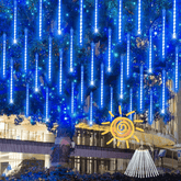 Blue meteor shower lights hanging in a tree outside a shopping mall at night