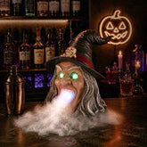 Halloween witch decor with glowing green eyes, wide open mouth, long gray hair, black pointed hat with skull, spooky indoor setting