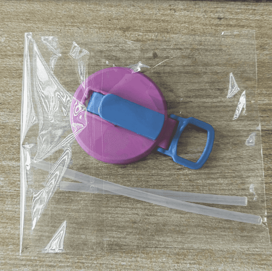Pink and blue retractable lid with two straws on a wooden surface