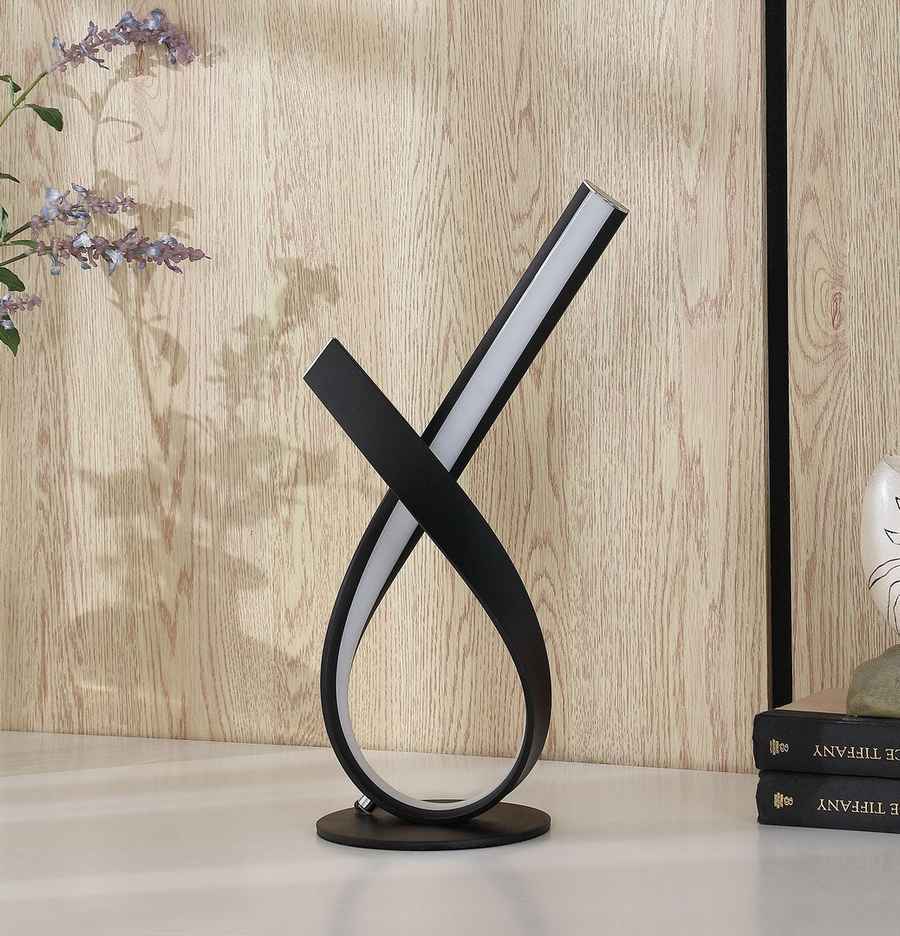 Modern black and white table lamp on a wooden surface with a light wood panel background
