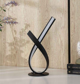 Modern black and white table lamp on a wooden surface with a light wood panel background