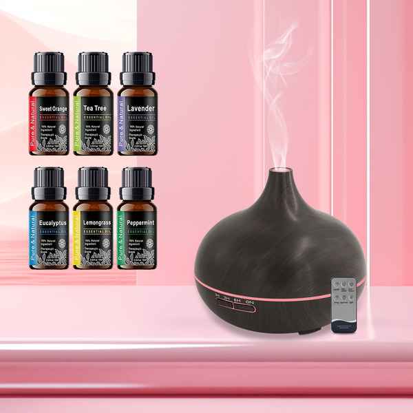 A black essential oil diffuser with a pink LED ring and rising steam, shown next to a small remote control. Six amber essential oil bottles labeled Sweet Orange, Tea Tree, Lavender, Rosemary, Eucalyptus, Lemongrass, and Peppermint are arranged on the left against a pink background.