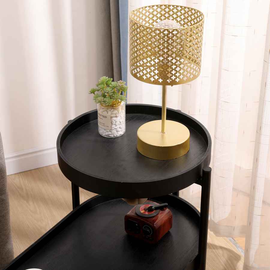 Black round side table with a gold lamp and decorative items in a room.