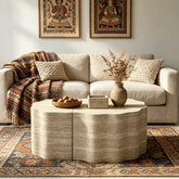 Living room wall with framed artwork, beige sofa with pillows, and a textured side table with a vase and decorative items