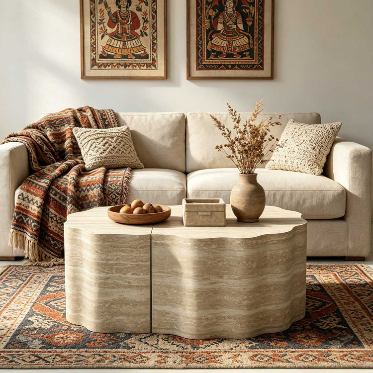 Living room wall with framed artwork, beige sofa with pillows, and a textured side table with a vase and decorative items