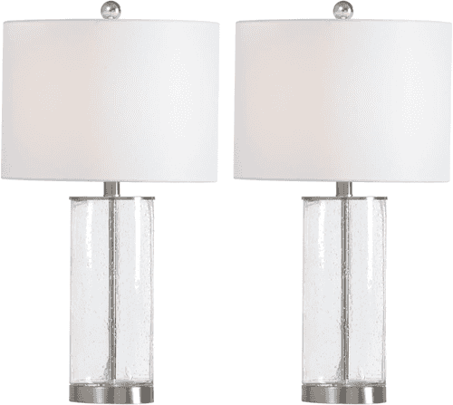 A pair of table lamps with white drum shades, clear seeded glass cylindrical bases, and polished silver metal accents on a white background.