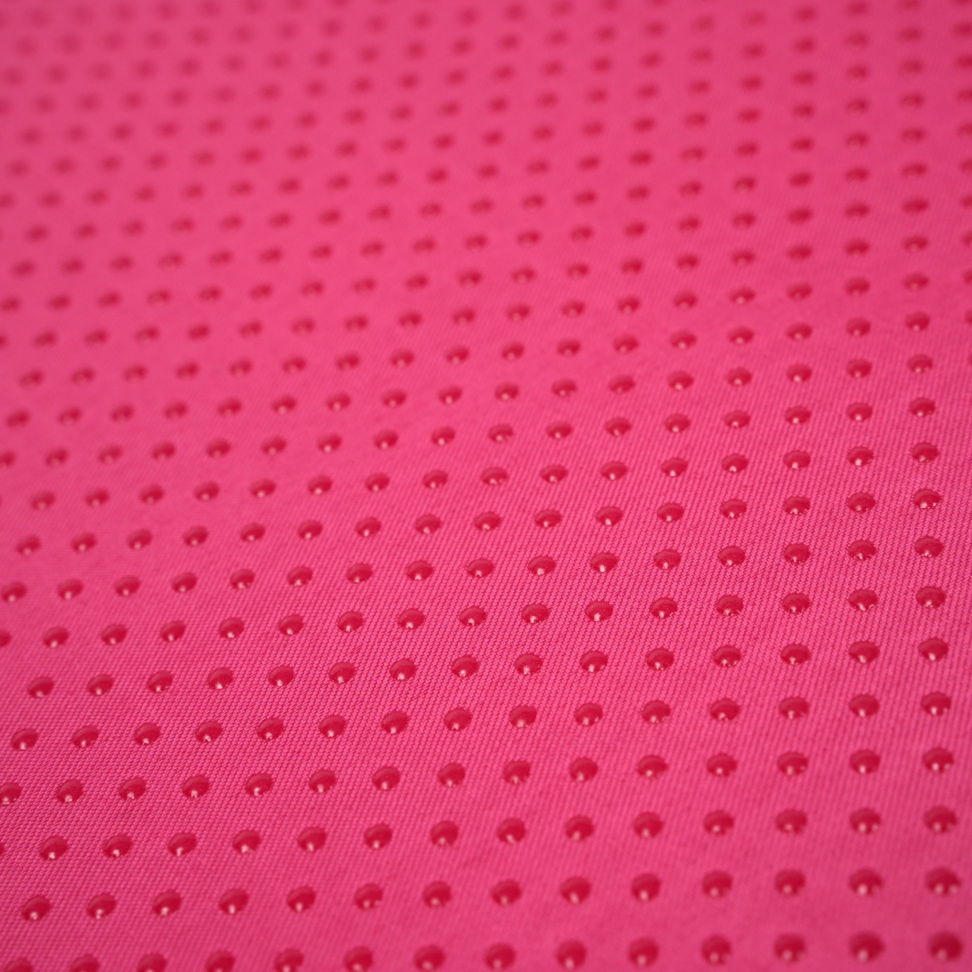 Close-up of anti-slip dotted base on pink ergonomic memory foam posture support pillow for enhanced grip and stability.