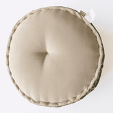 Round beige cushion with a visible brand tag on a white background