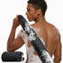 Man with soap suds on his back holding a black mesh scrubber.