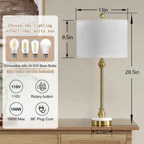 A table lamp with a white drum shade, gold-toned stem and base details, and a white round base, shown on a wooden table with overlaid dimension labels (13 in, 9.5 in, 28.