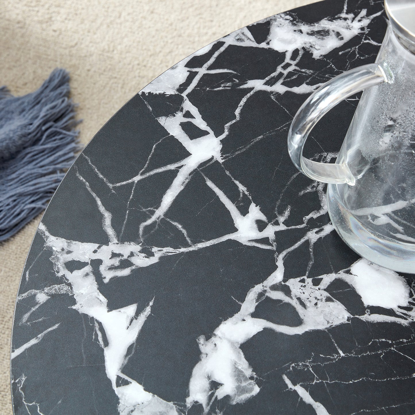 Close-up of black MDF round coffee table surface with white marble veining, highlighting its modern minimalist texture.
