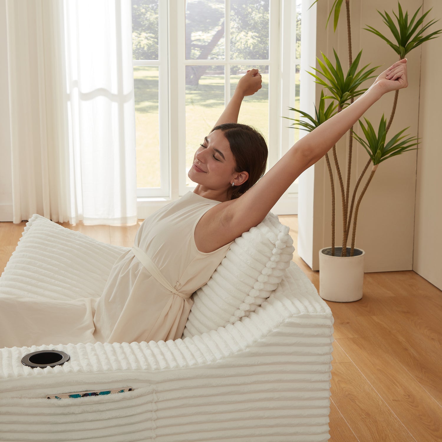 Woman relaxing on a white inflatable massage chair in a bright room with large windows.