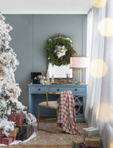 Decorated living room with Christmas tree, wreath, and gifts against a blue wall.