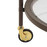 Close-up of a round glass table with a gold metal leg and black wheel on a white background