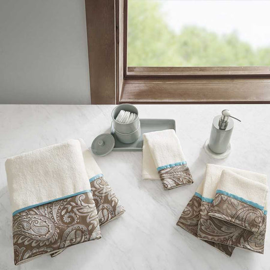 Elegant Jacquard Towel Set with 100% cotton in beige and taupe paisley design, displayed on a marble counter with bathroom accessories.