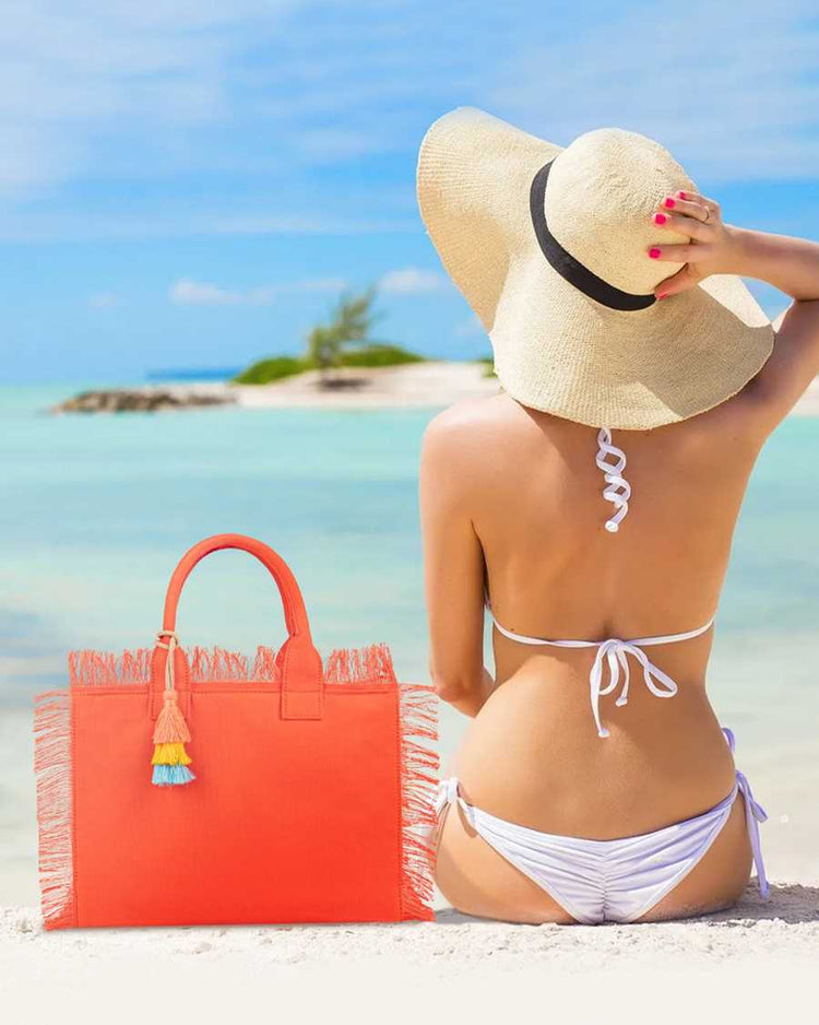 Woman in white bikini and sun hat with orange bag on a beach