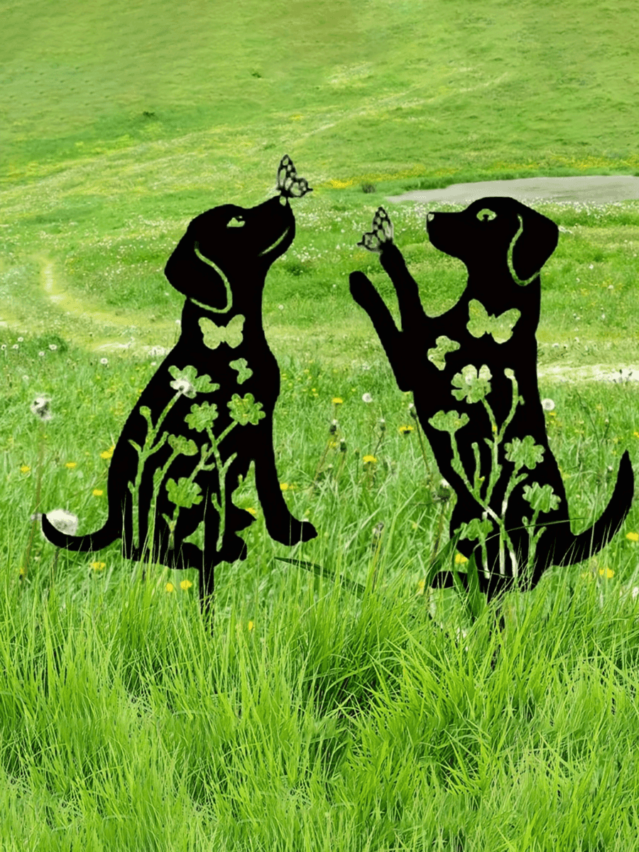 Metallic black dog sculptures with floral patterns on a grassy field