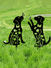Metallic black dog sculptures with floral patterns on a grassy field