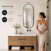 Woman standing in a bathroom with a large oval mirror and vanity, showing mirror size measurements.