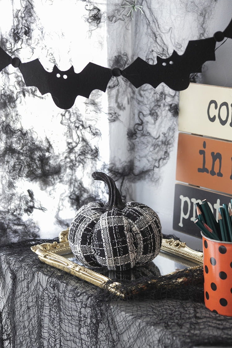 Decorative Halloween setup with black and white pumpkin, bats, and spider webs.