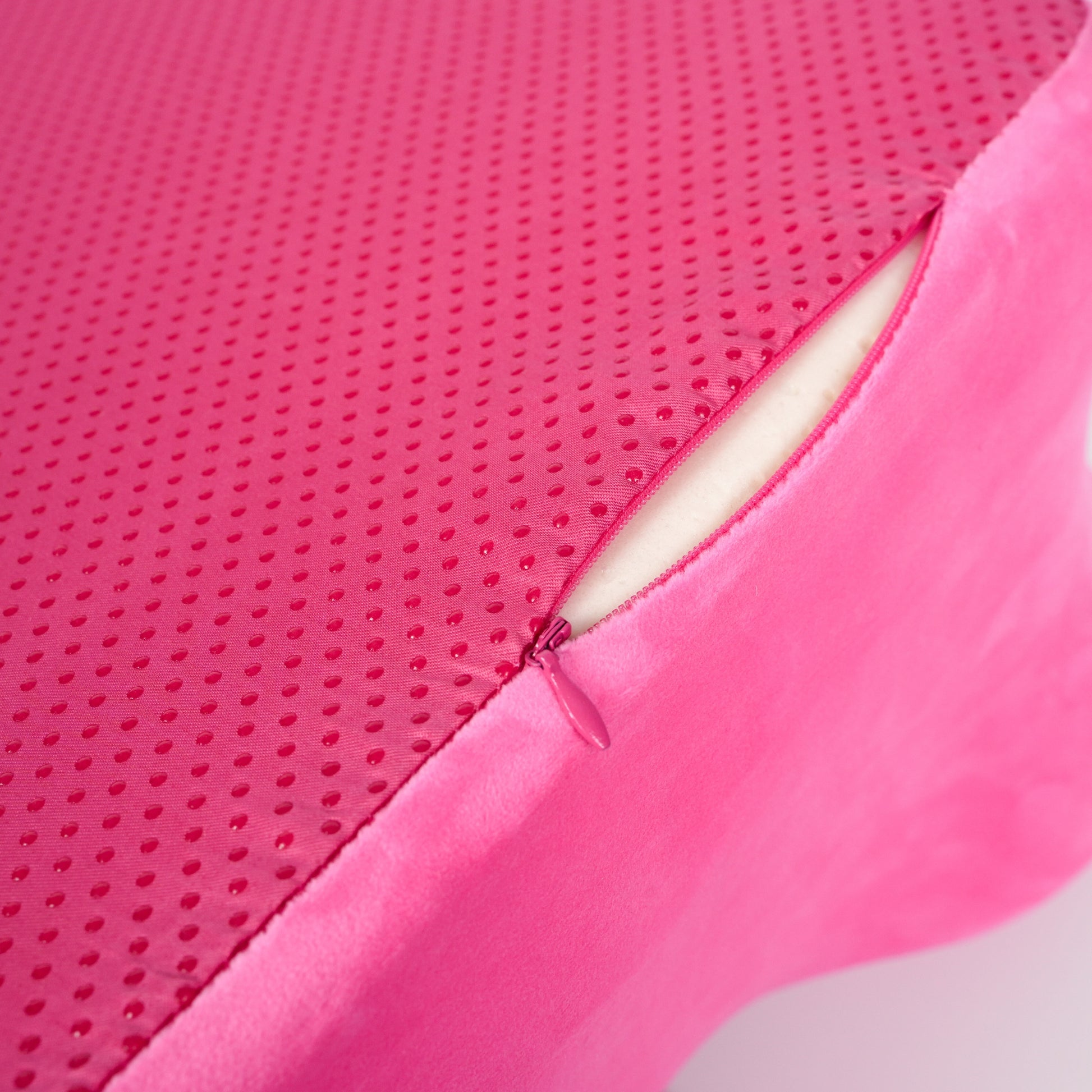Bottom view of pink memory foam pillow showing anti-slip dotted fabric and zippered opening for secure and stable use.