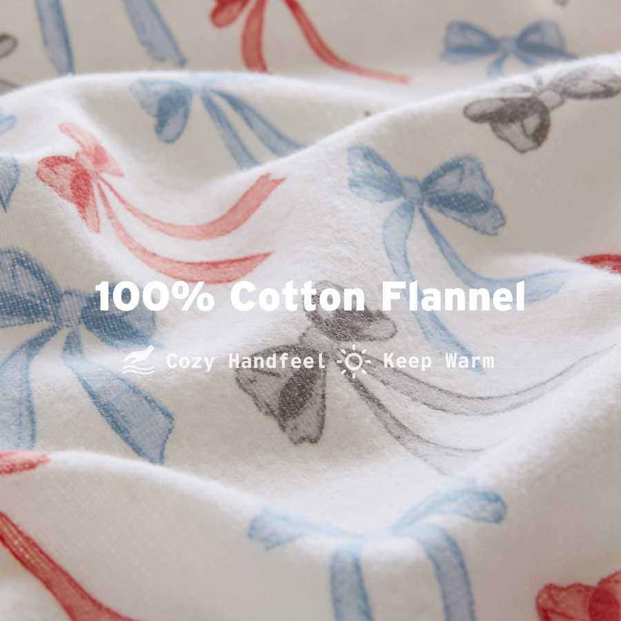 Close-up of Happy Bows Twin XL Cotton Flannel Sheet Set fabric texture with red, blue, and gray bows on soft white background.
