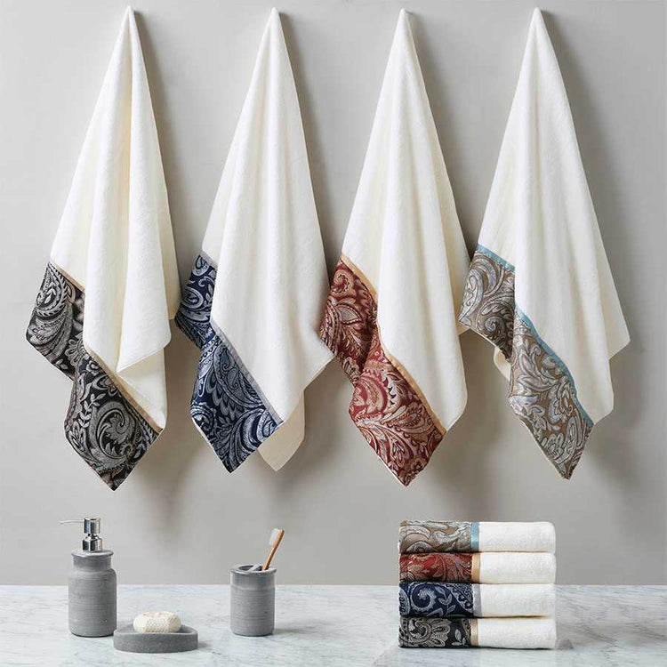 Elegant Jacquard Towel Set in four color variations hanging on wall hooks, showcasing paisley borders and soft cotton texture.